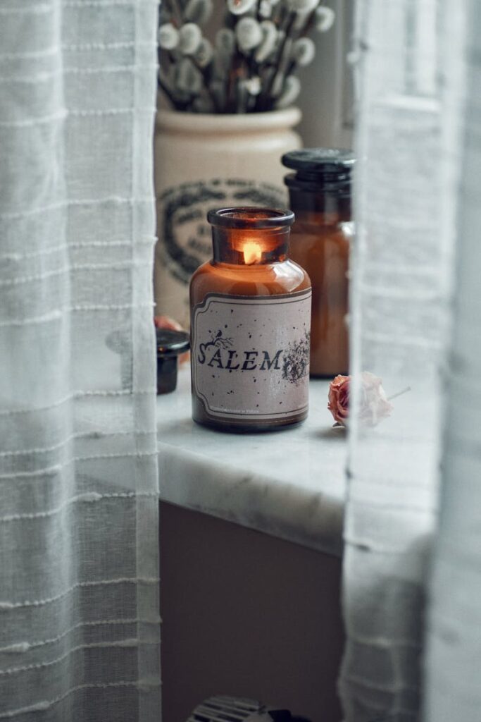 A jar of essential oils sits on a window sill